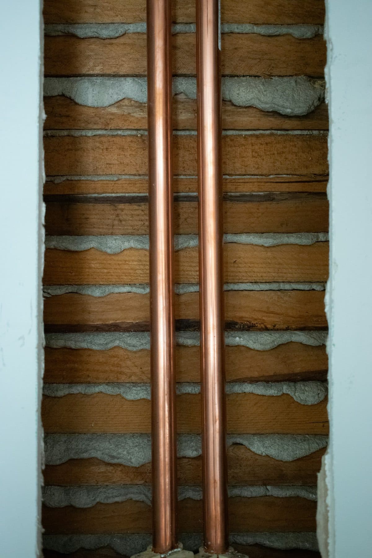 Zwei Kupferrohre in einer aufgerissenen Wand